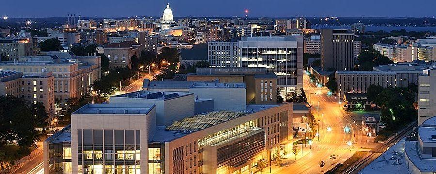 A photo of the UW-Madison campus at night with the Wisconsin state capital in the background