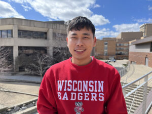Photo of Tenzin Phuntsok wearing a red Wisconsin Badger sweatshirt and smiling